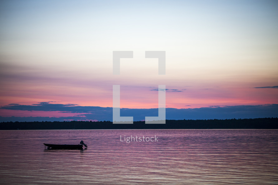 boat anchored on a lake at sunset 