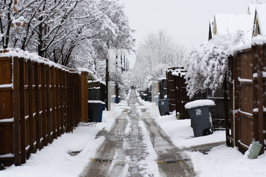 snow covered alley between houses 
