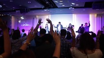 raised hands during a worship service and people on stage 
