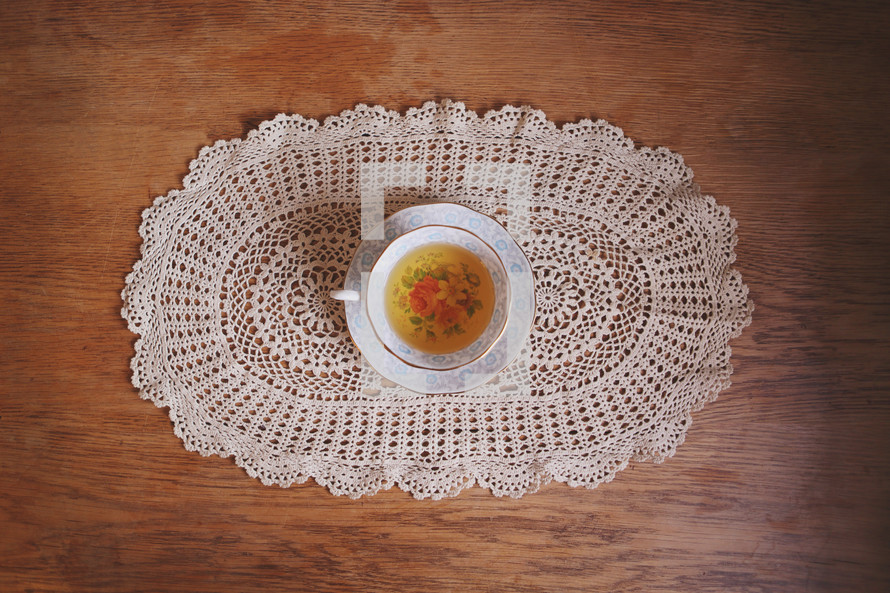 a cup of tea in grandma's cup on hand crocheted lace and old table
