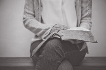 a woman sitting reading a Bible in her lap 