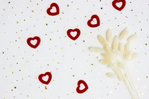 red hearts, gold confetti, and dried fuzzy grasses 