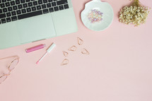 makeup and paper clips on a feminine pink computer desk 