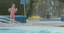 Slow motion shot of a little girl playing in a swimming pool during summer