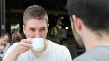 two men in conversation over coffee