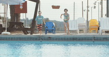 Super slow motion shot of boy and a girl playing and jumping in a swimming pool
