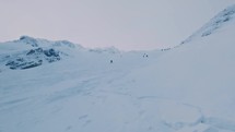 Panorama of winter alps mountain with people touring on ski to the top of frozen rocky peak in snowy season
