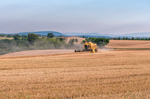 Summertime - harvest. Harvester on field at sunset. Modern agriculture equipment. Seasonal works