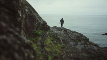 a man walking along a rocky shore 