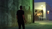 man walking on sidewalk alone at night 