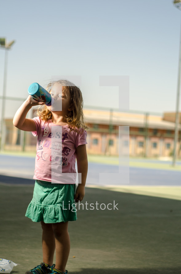 A young girl drinking from a water bottle.