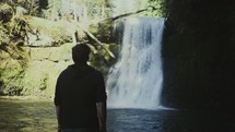 a man watching a waterfall outdoors 