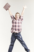 A boy jumping with a bible in his hand