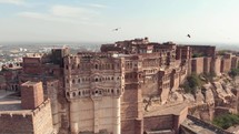 Aerial drone footage tilting down a large palace on top of a hill above the vast city of Jodhpur, India. 