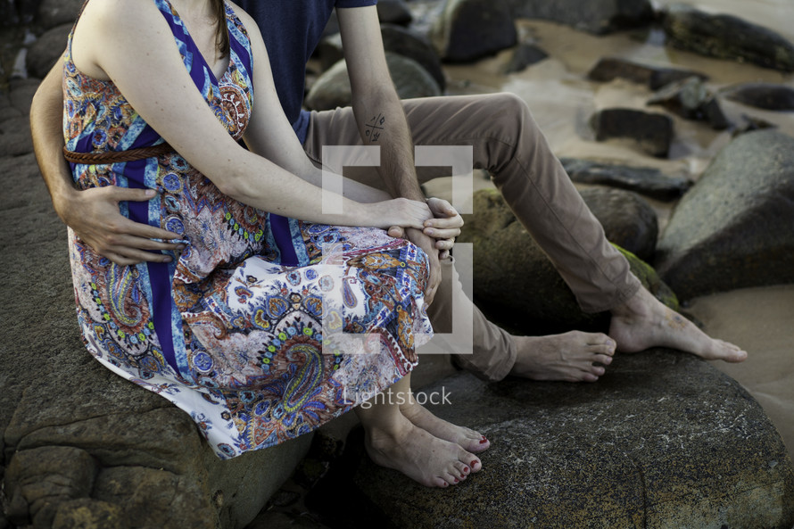 a couple holding hands sitting on rocks 