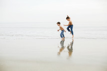brothers running on a beach in jeans 