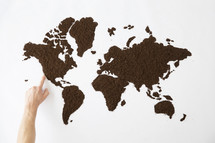 finger pointing to a world map made of dirt.