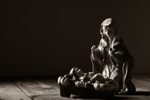 Mother Mary over baby Jesus in a manger figurine 
