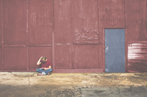 man reading outdoor in front of a red building