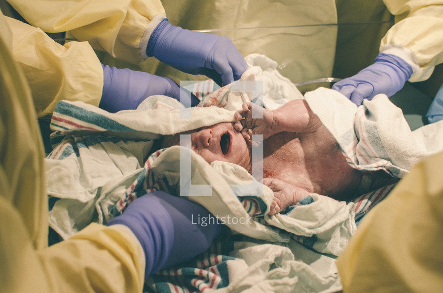 Newborn baby being cleaned by hospital staff.