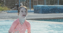 Slow motion shot of a little girl playing in a swimming pool during summer