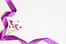pink flowers with purple ribbon on white 