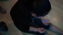 a girl sitting on a floor praying during a worship service 