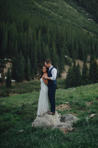 bride and groom standing on a mountainside 