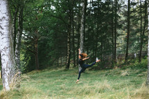 a woman dancing in a forest 