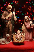 holy family figurines and colorful bokeh Christmas lights 