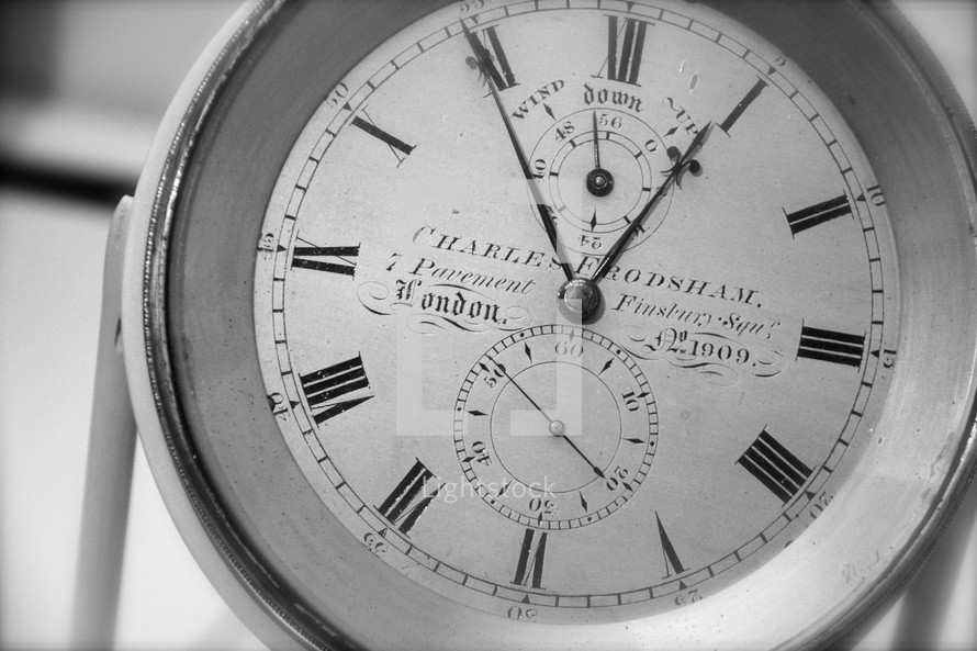 roman numerals clock or pocket watch showing five minutes before one o clock 