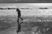 a girl child in rain boots walking on a shore 