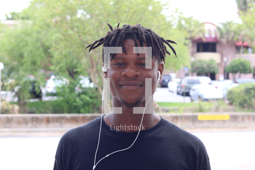 face of an African American man with earbuds and dreads 