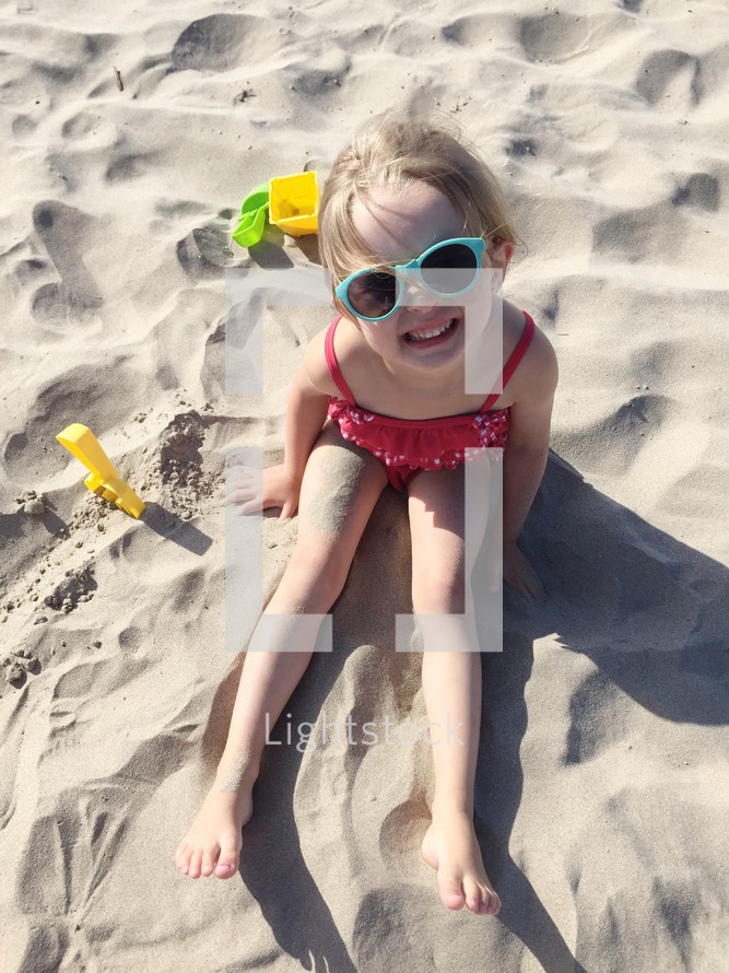 girl toddler sitting in the sand on a beach 