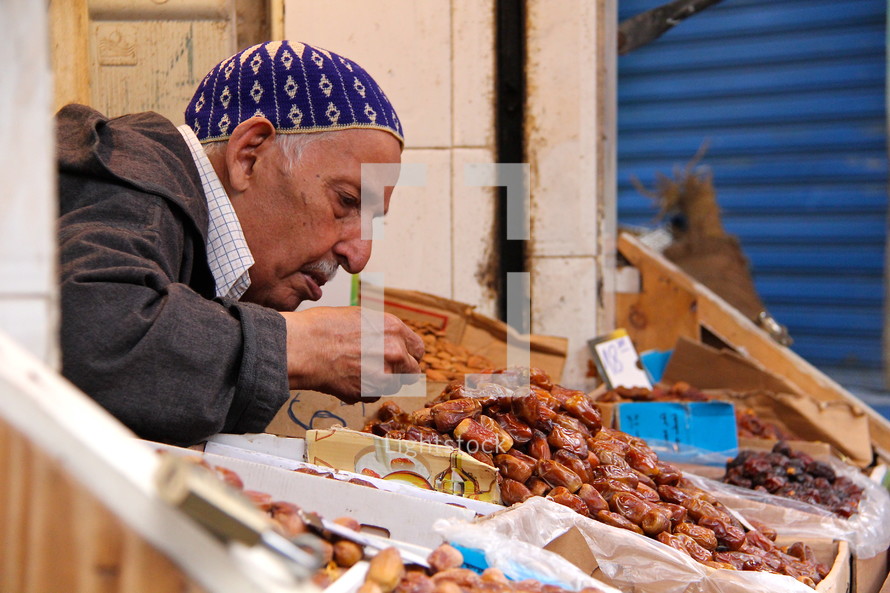 Man inspecting dates at an open, outside market.