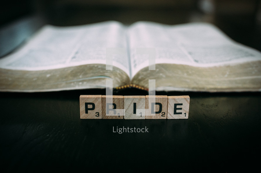open Bible and the word pride in scrabble pieces 