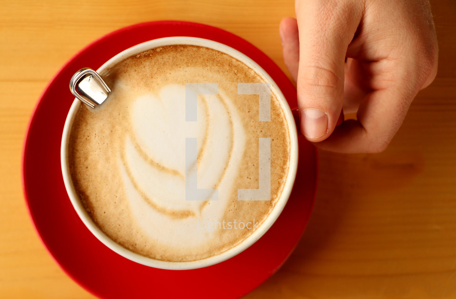 hand on a mug of cappuccino 