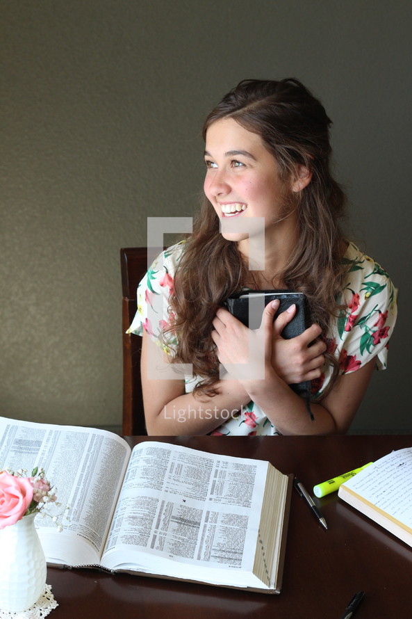 A smiling girl holding a Bible.