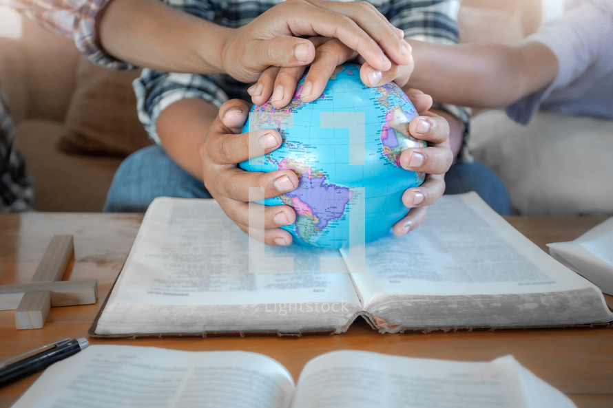hands on a globe at a small group Bible study 
