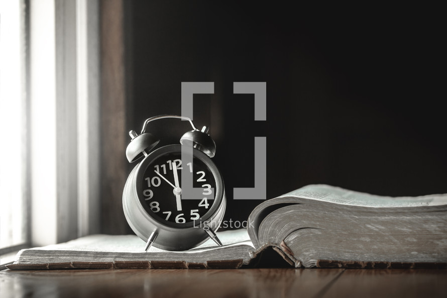 alarm clock on an open Bible 