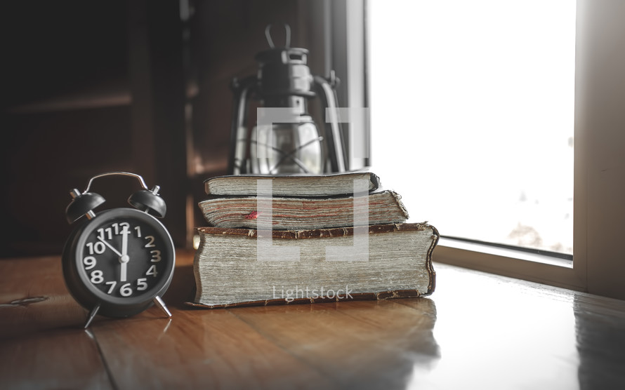 alarm clock and Bibles in a window 