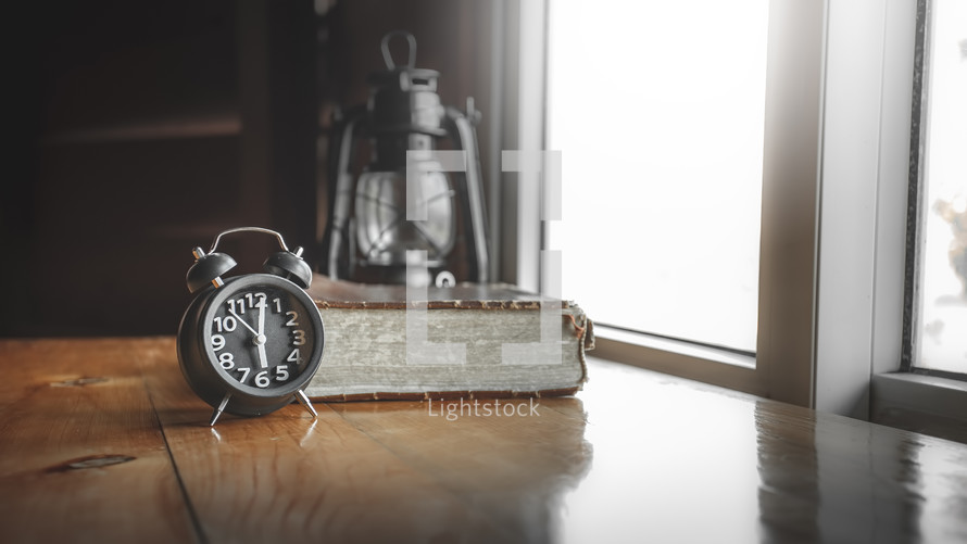 alarm clock, Bible, oil lamp in a window 