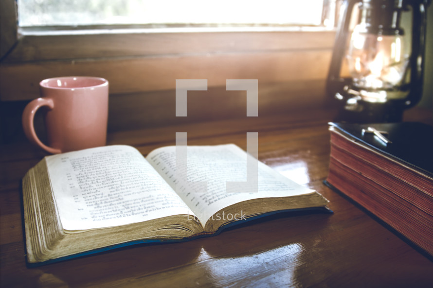 open bible for morning devotion on wooden table with sunlight