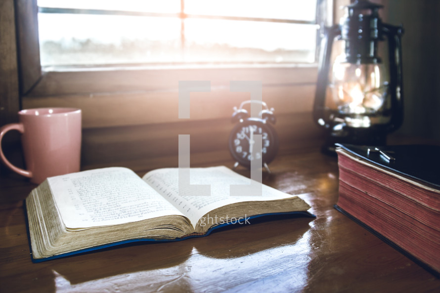 open Bible in a window with a coffee cup in morning sunlight 