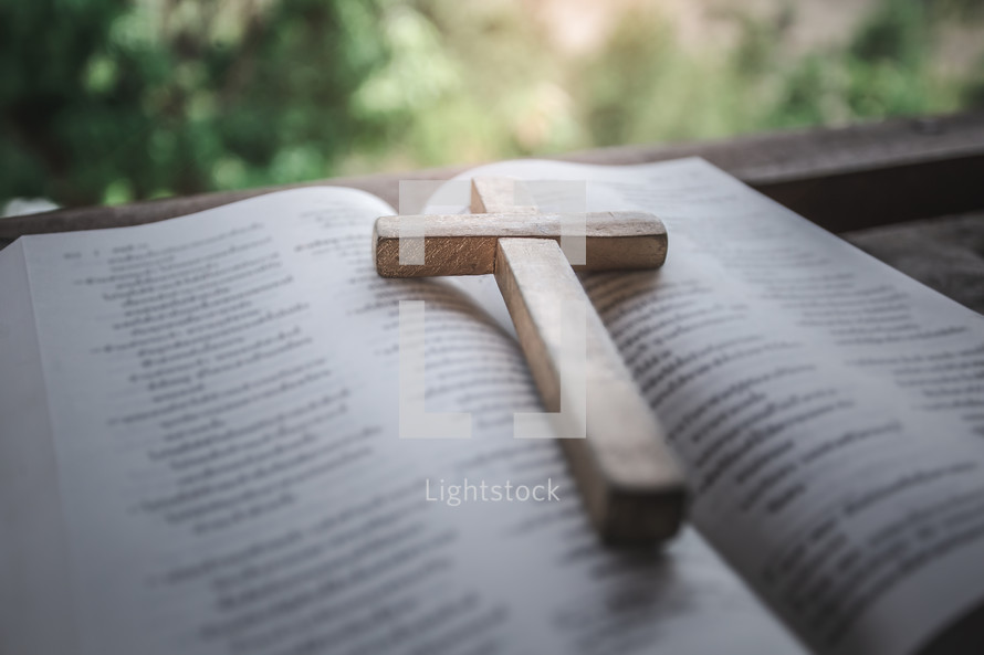 a wooden cross on the pages of a Bible 