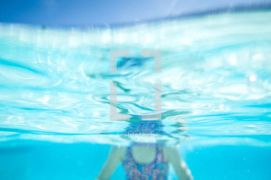 a girl child swimming under water in a pool 
