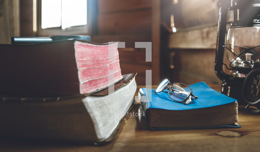 magnifying glass and reading glasses on a stack of Bibles 