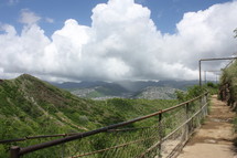 a fence lined trail along a mountainside 