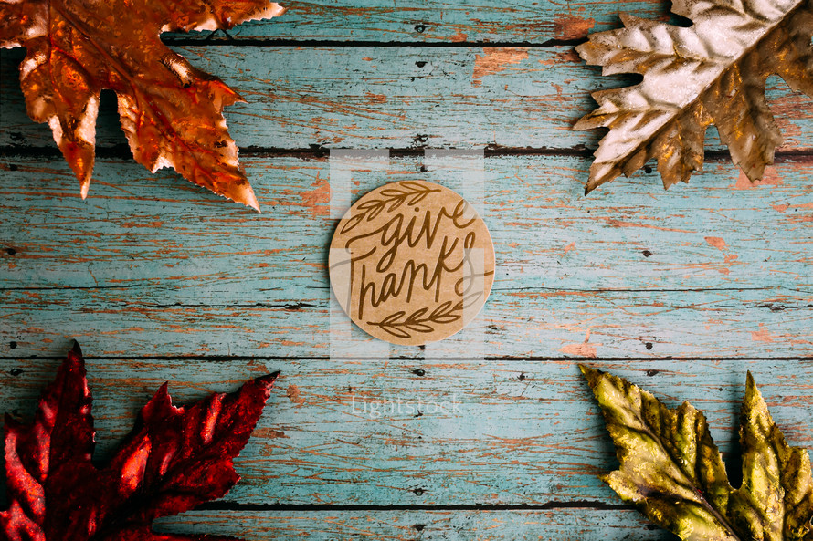 give thanks on teal wood boards and metallic fall leaves 