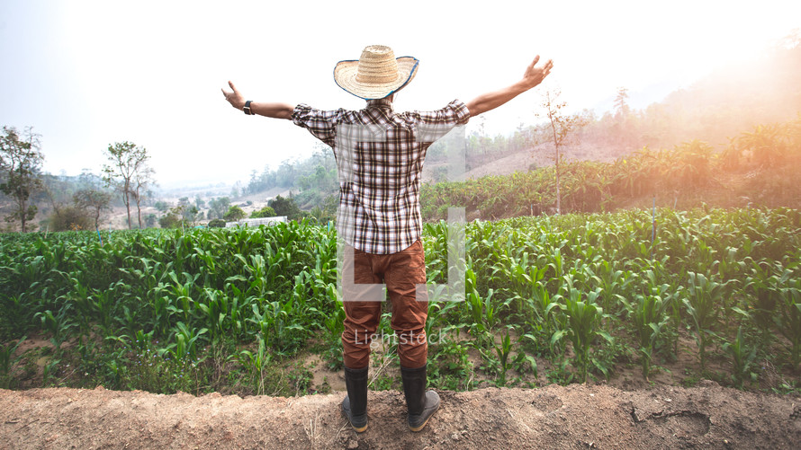 a farmer with outstretched arms standing in a field 